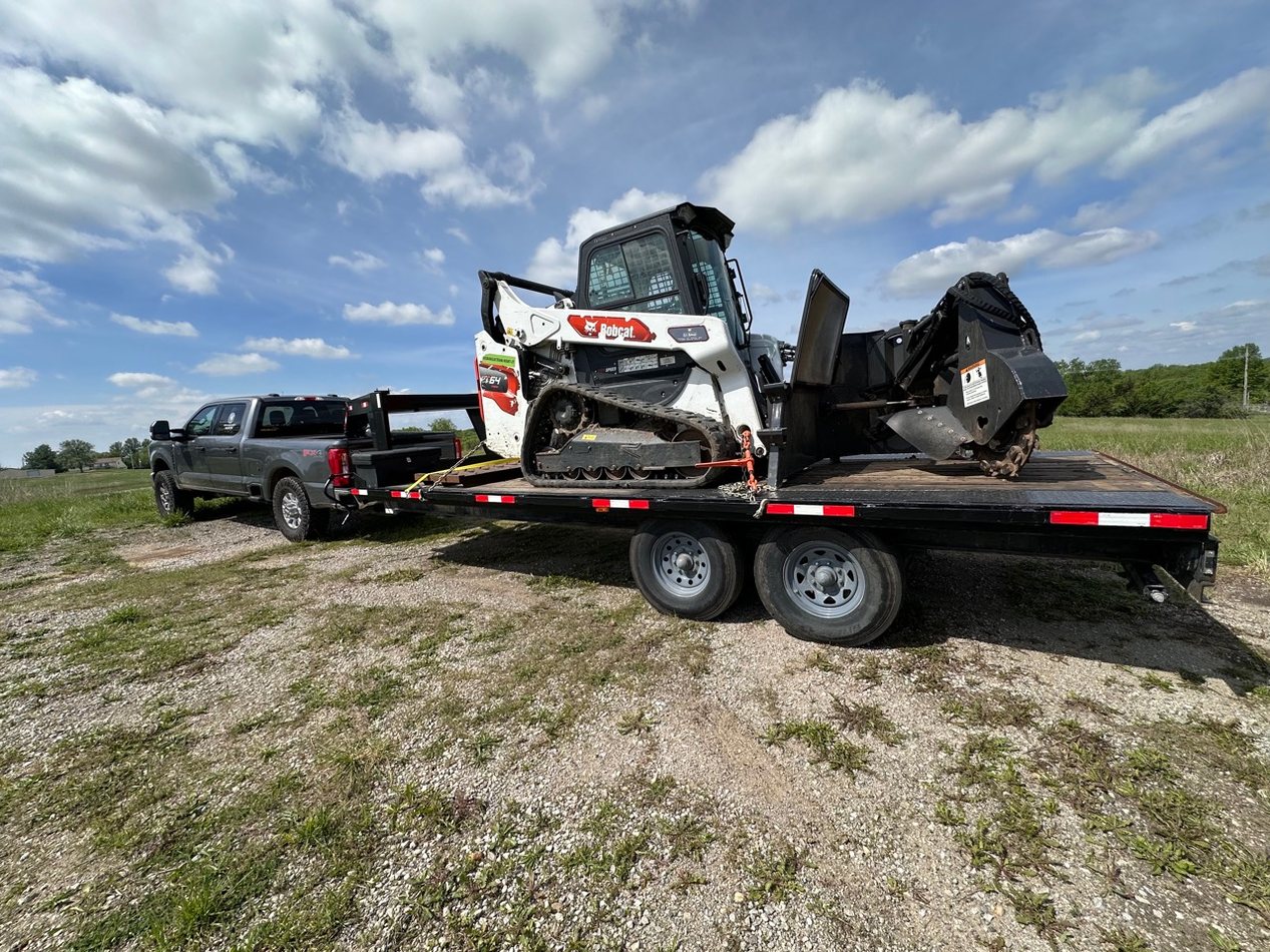 Track loader and brush cutting attachment on a trailer