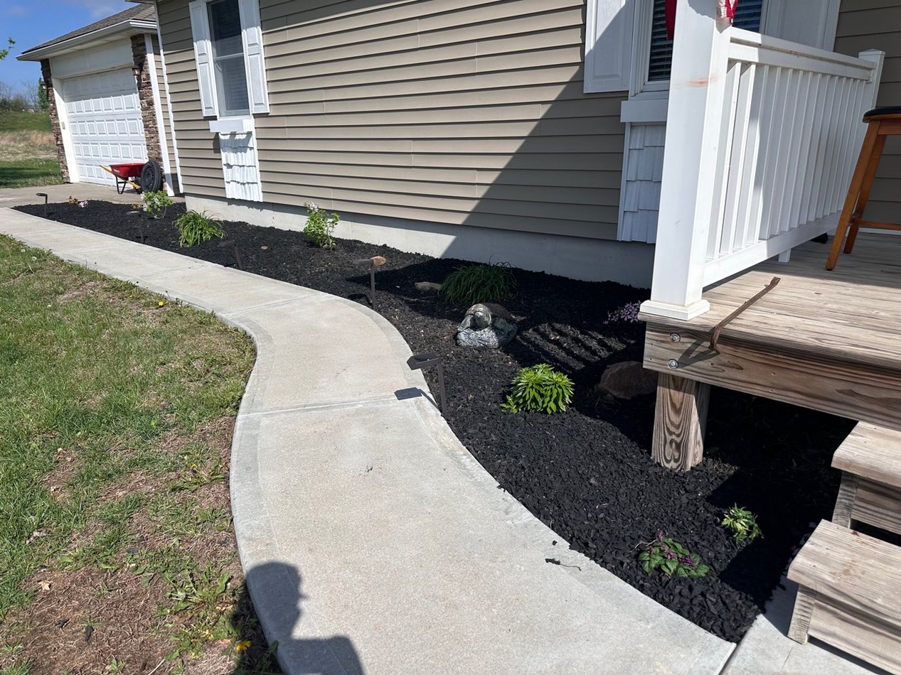 Fresh black mulch and edged landscape bed beside a home